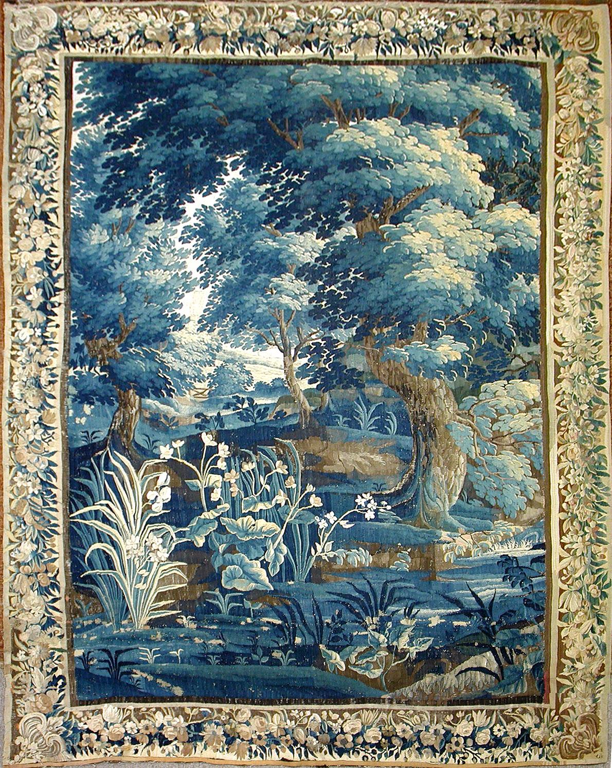 Full view of 18th-century French Verdure tapestry showing lush landscape and architectural elements.